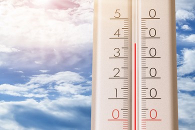 Image of High temperature on thermometer against blue sky on sunny day. Summer weather