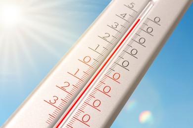 Image of Extremely high temperature on thermometer against blue sky on sunny day. Summer weather