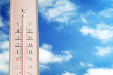 Image of High temperature on thermometer against blue sky on sunny day. Summer weather