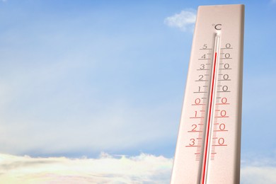 Image of Extremely high temperature on thermometer against blue sky on sunny day. Summer weather