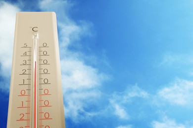 Image of High temperature on thermometer against blue sky on sunny day. Summer weather