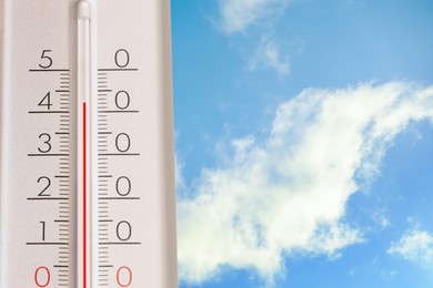Image of High temperature on thermometer against blue sky on sunny day. Summer weather