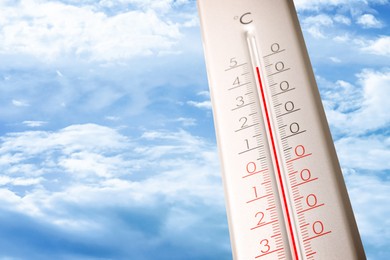 Image of High temperature on thermometer against blue sky on sunny day. Summer weather