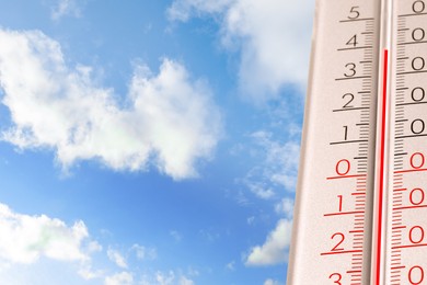 Image of High temperature on thermometer against blue sky on sunny day. Summer weather