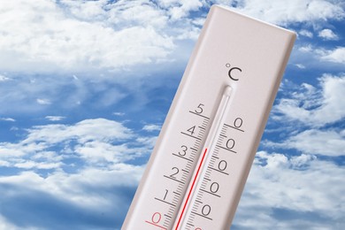 Image of High temperature on thermometer against blue sky on sunny day. Summer weather