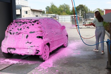 Photo of Woman washing auto with foam at car wash