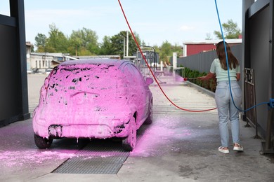Photo of Woman washing auto with foam at car wash