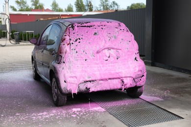 Photo of Auto covered with cleaning foam at outdoor car wash