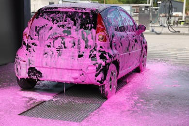 Photo of Auto covered with cleaning foam at outdoor car wash