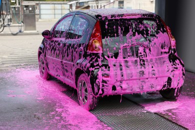 Photo of Auto covered with cleaning foam at outdoor car wash