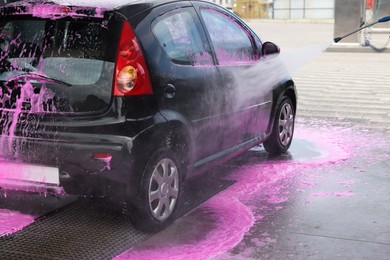 Photo of Washing auto with high pressure water jet at car wash, closeup