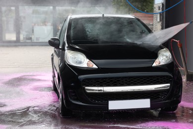 Photo of Washing auto with high pressure water jet at car wash, closeup