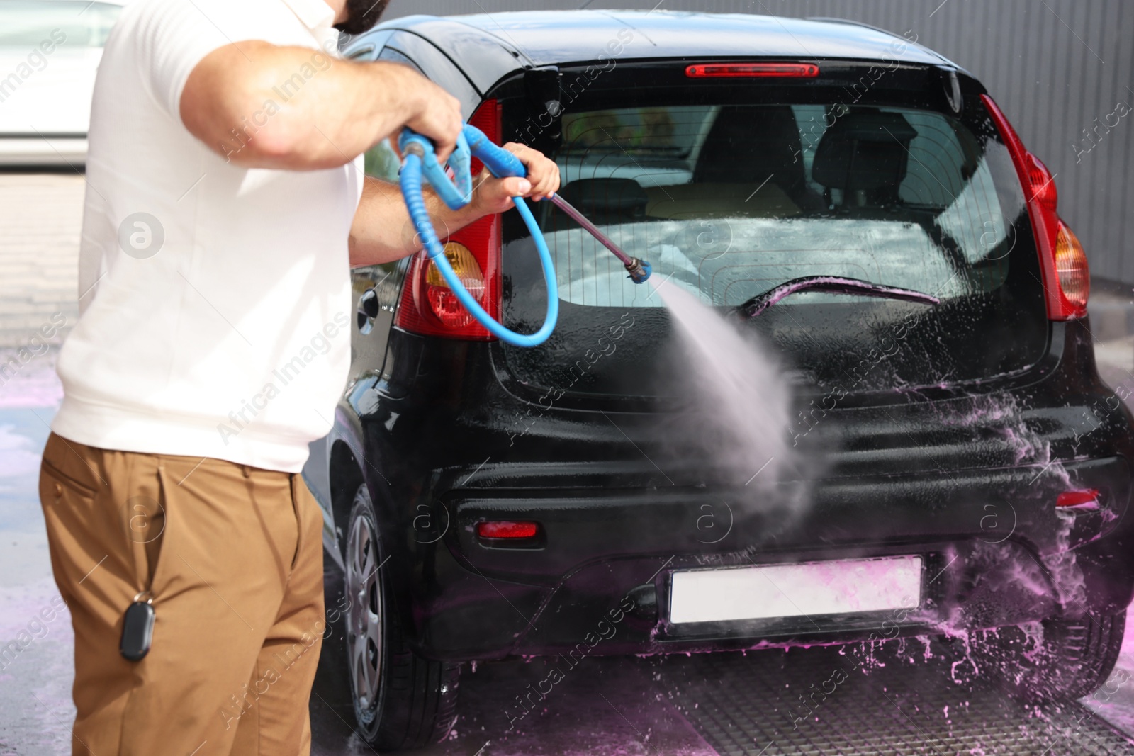 Man washing auto with high pressure water jet at car wash, closeup Photo of Man washing auto with high pressure water jet at car wash, closeup