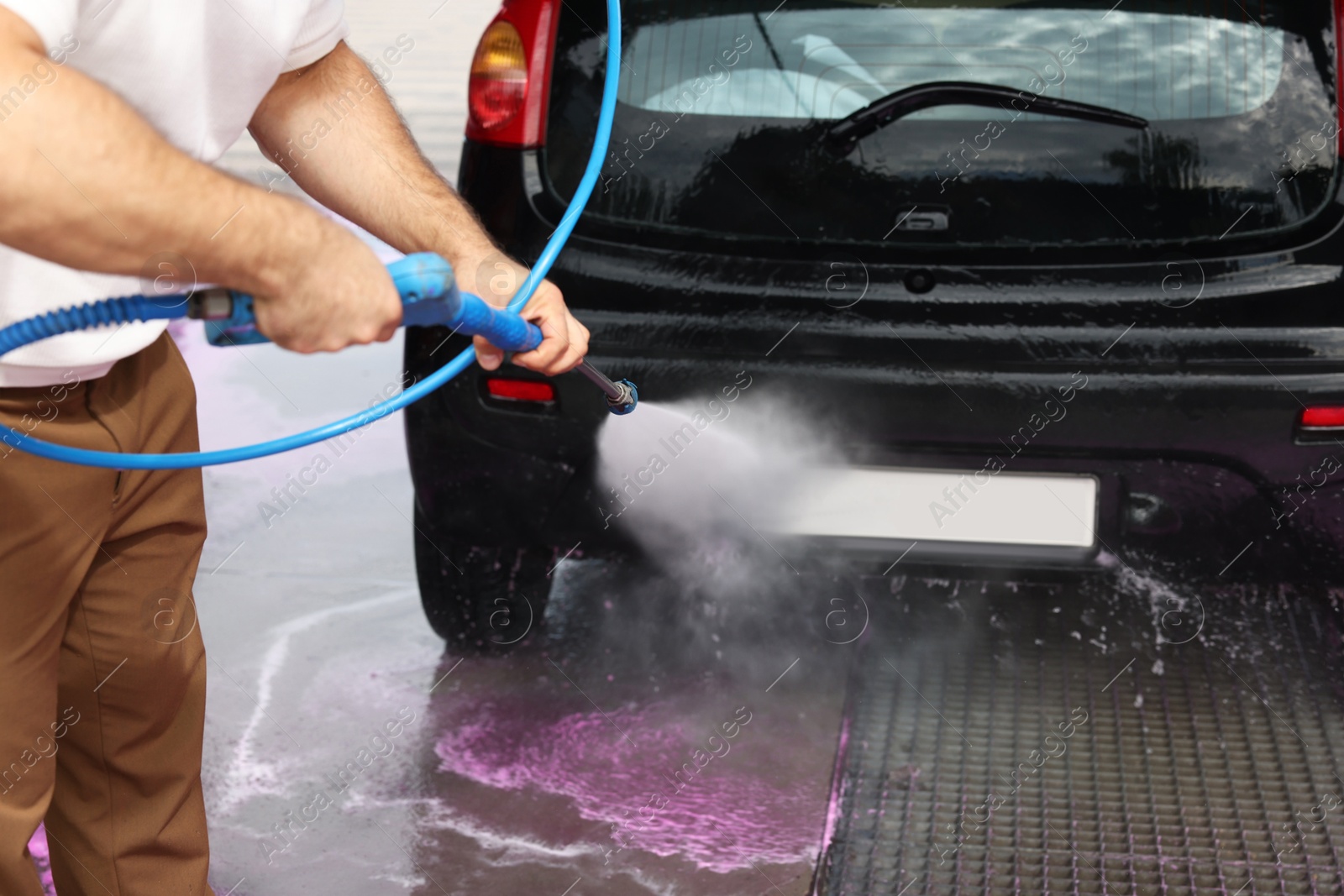 Man washing auto with high pressure water jet at car wash, closeup Photo of Man washing auto with high pressure water jet at car wash, closeup