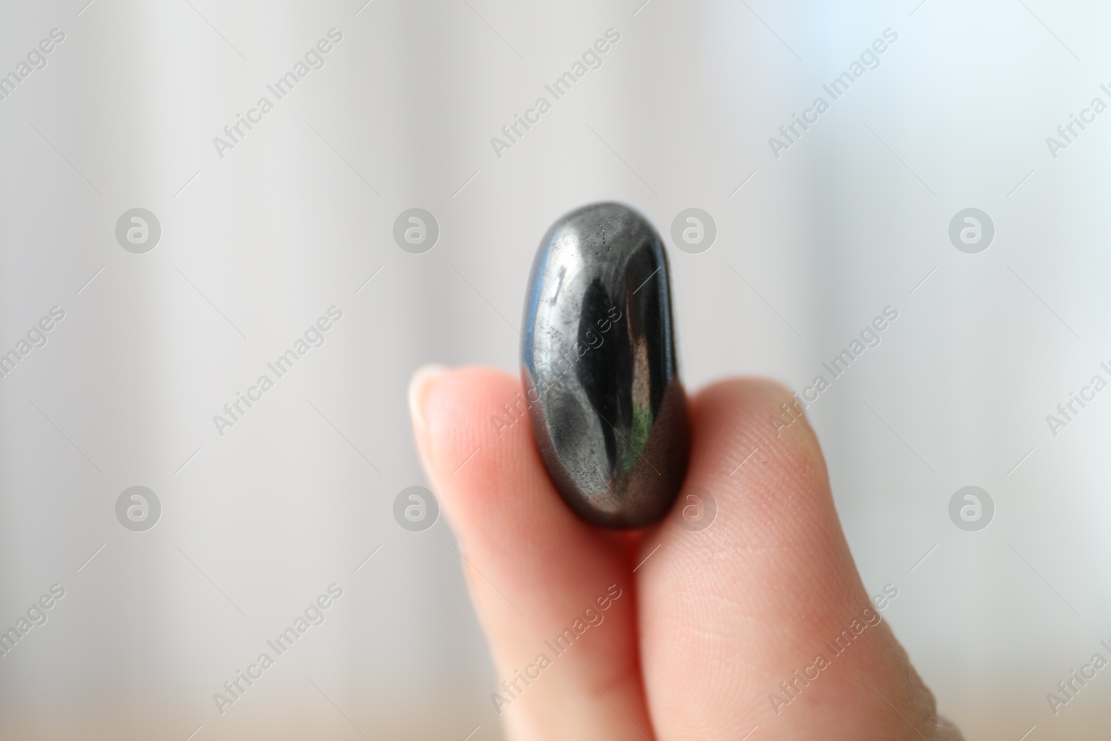 Photo of Woman with healing stone on blurred background, closeup