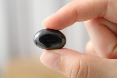 Photo of Woman with healing stone on blurred background, closeup
