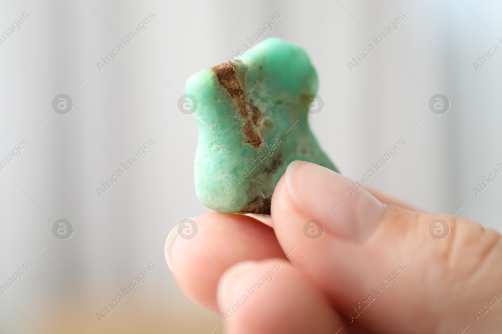 Photo of Woman with healing stone on blurred background, closeup