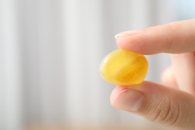 Photo of Woman with healing stone on blurred background, closeup. Space for text