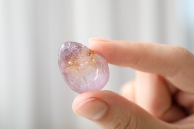 Photo of Woman with healing stone on blurred background, closeup