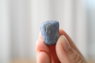 Photo of Woman with healing stone on blurred background, closeup