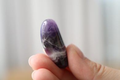 Photo of Woman with healing stone on blurred background, closeup
