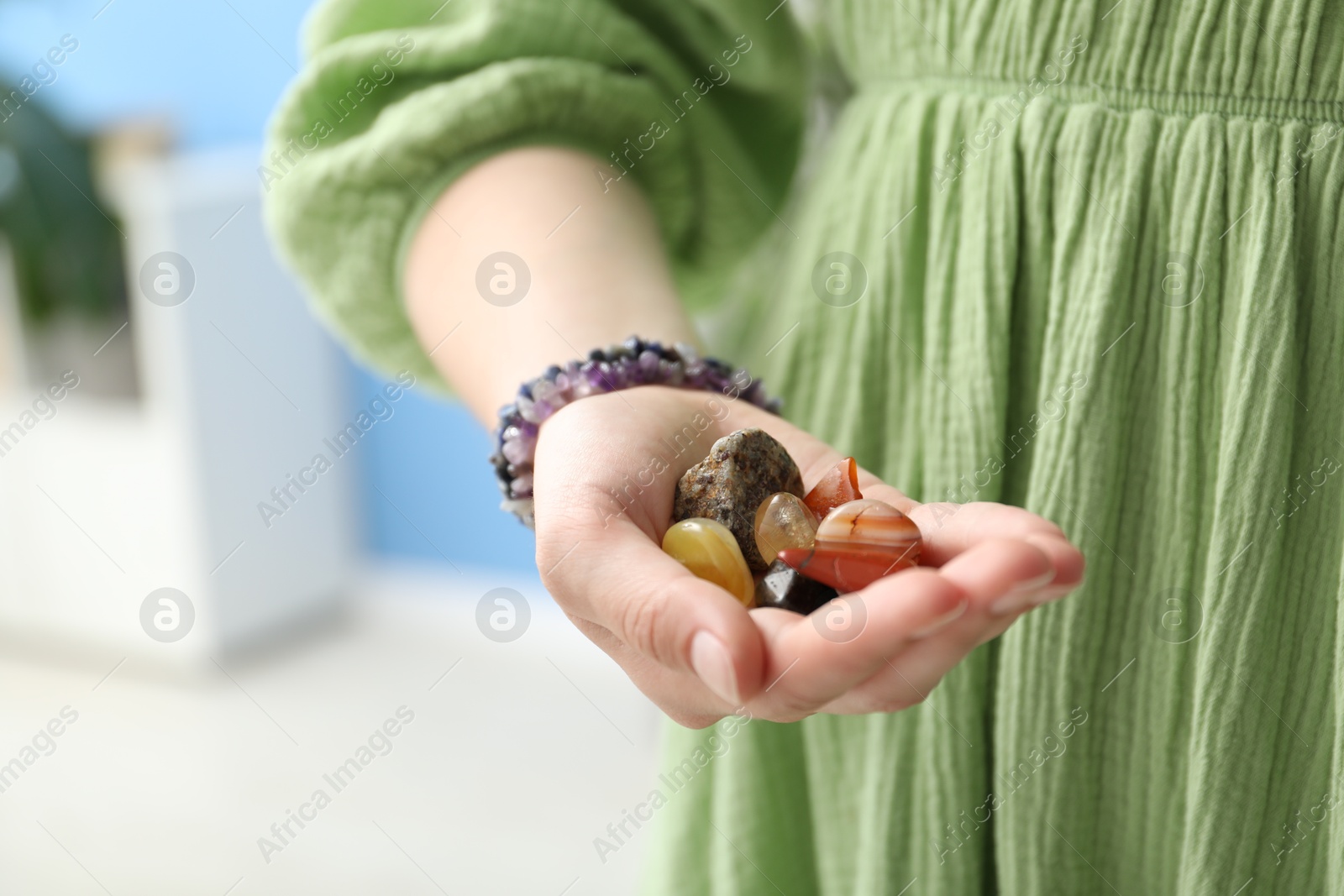 Woman with healing stones on blurred background, closeup Photo of Woman with healing stones on blurred background, closeup