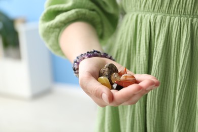 Photo of Woman with healing stones on blurred background, closeup