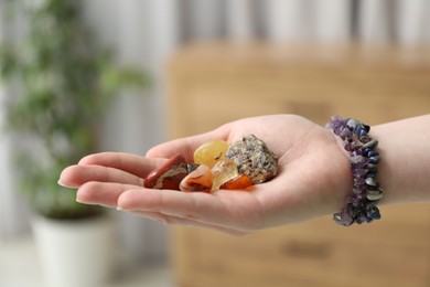 Photo of Woman with healing stones on blurred background, closeup