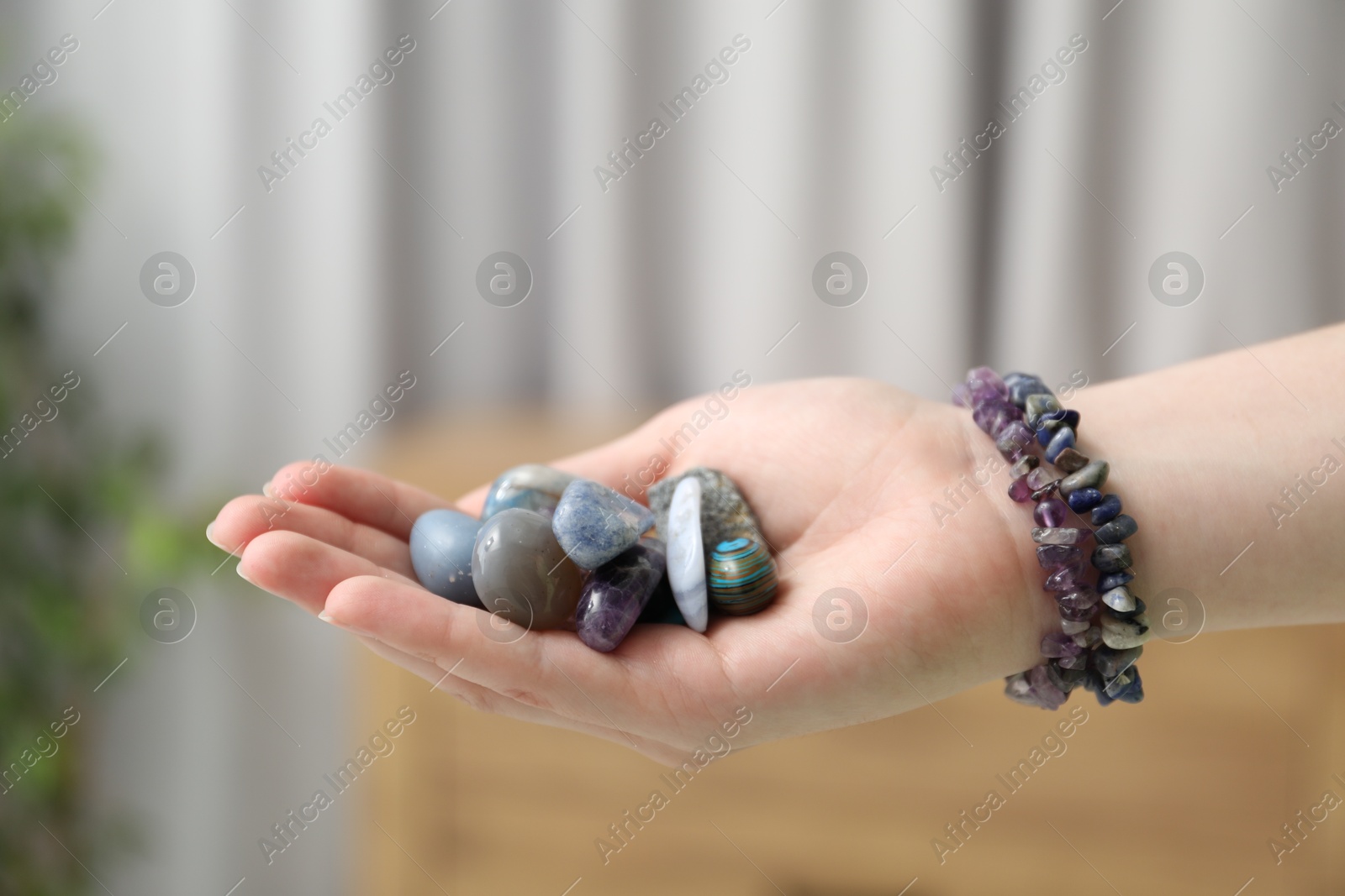 Woman with healing stones on blurred background, closeup Photo of Woman with healing stones on blurred background, closeup
