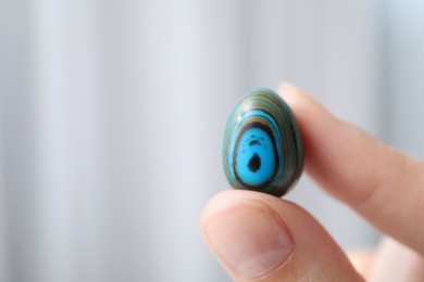 Photo of Woman with healing stone on blurred background, closeup. Space for text