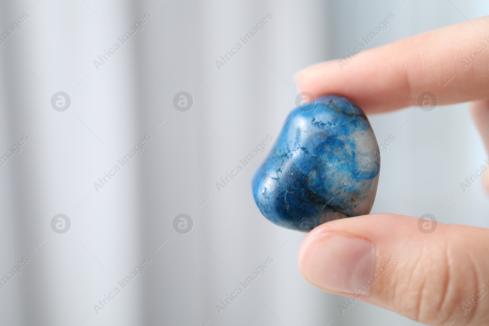 Woman with healing stone on blurred background, closeup. Space for text Photo of Woman with healing stone on blurred background, closeup. Space for text