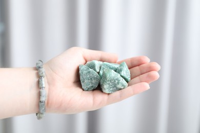 Photo of Woman with healing stones on blurred background, closeup