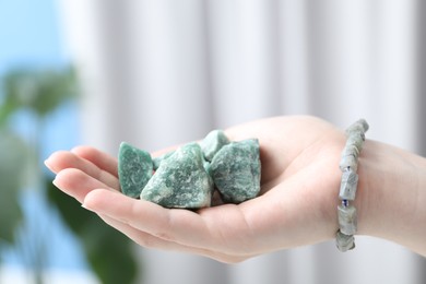 Photo of Woman with healing stones on blurred background, closeup