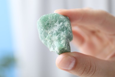 Photo of Woman with healing stone on blurred background, closeup