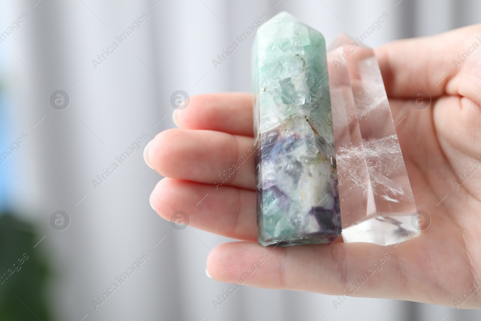 Photo of Woman with healing crystals on blurred background, closeup