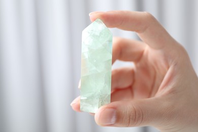 Photo of Woman with healing crystal on blurred background, closeup