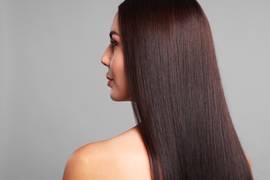 Photo of Woman with beautiful smooth hair after lamination procedure on light grey background, back view. Space for text