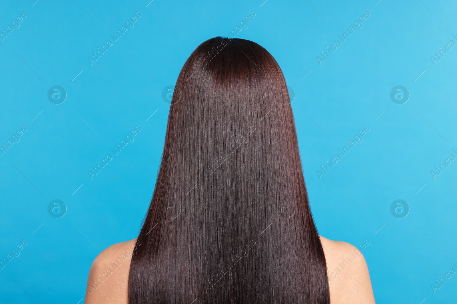Photo of Woman with beautiful smooth hair after lamination procedure on light blue background, back view