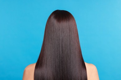Photo of Woman with beautiful smooth hair after lamination procedure on light blue background, back view