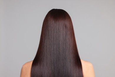 Photo of Woman with beautiful smooth hair after lamination procedure on light grey background, back view