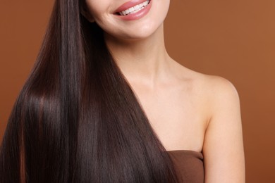 Photo of Woman with beautiful smooth hair after lamination procedure on brown background, closeup