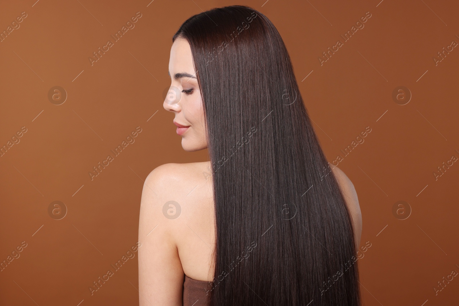 Photo of Woman with beautiful smooth hair after lamination procedure on brown background