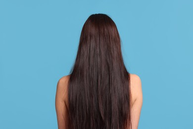 Photo of Woman with damaged hair before lamination procedure on light blue background, back view