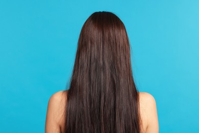 Photo of Woman with damaged hair before lamination procedure on light blue background, back view