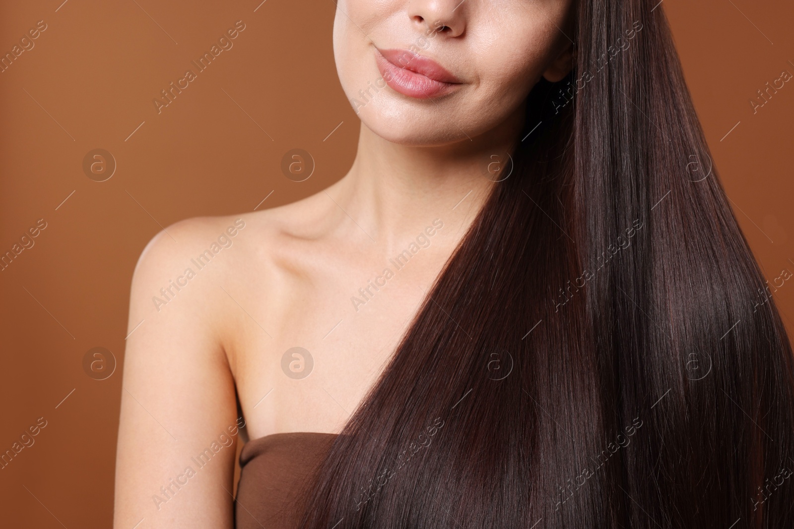 Photo of Woman with beautiful smooth hair after lamination procedure on brown background, closeup