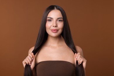 Photo of Woman with beautiful smooth hair after lamination procedure on brown background