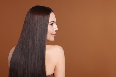 Photo of Woman with beautiful smooth hair after lamination procedure on brown background, space for text