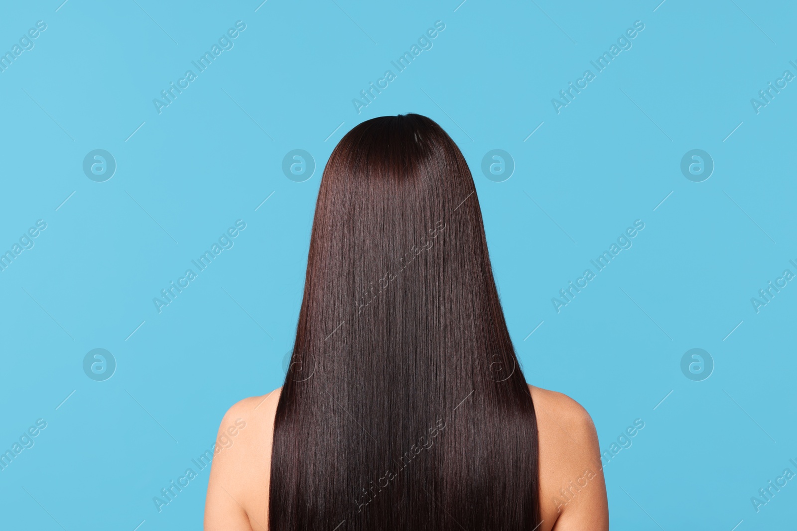 Photo of Woman with beautiful smooth hair after lamination procedure on light blue background, back view