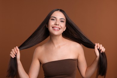 Photo of Woman with beautiful smooth hair after lamination procedure on brown background