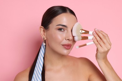 Photo of Beautiful woman with makeup brushes on pink background